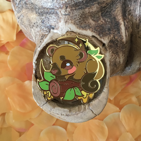 A hard enamel pin featuring the Kinkajou, alternatively called Honey Bear