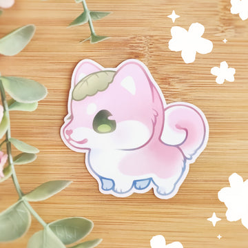 A photo featuring a vinyl sticker of the adorable Sakura Inu, a shiba inu with a pink, peachy coat